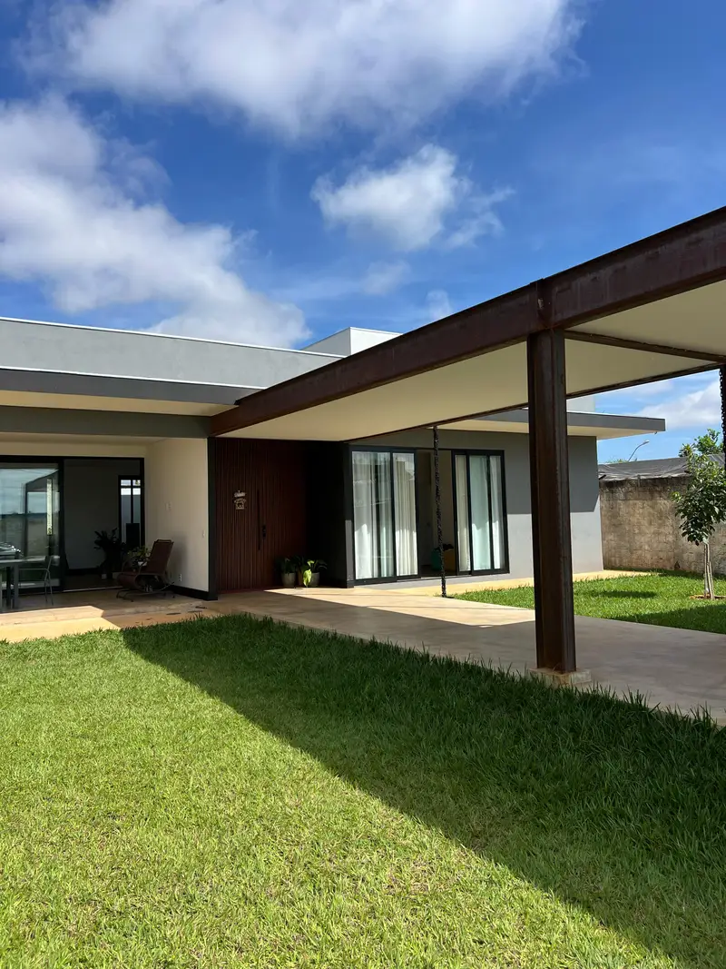 Fachada da residência com panos de vidro de piso a teto e beiral reto.