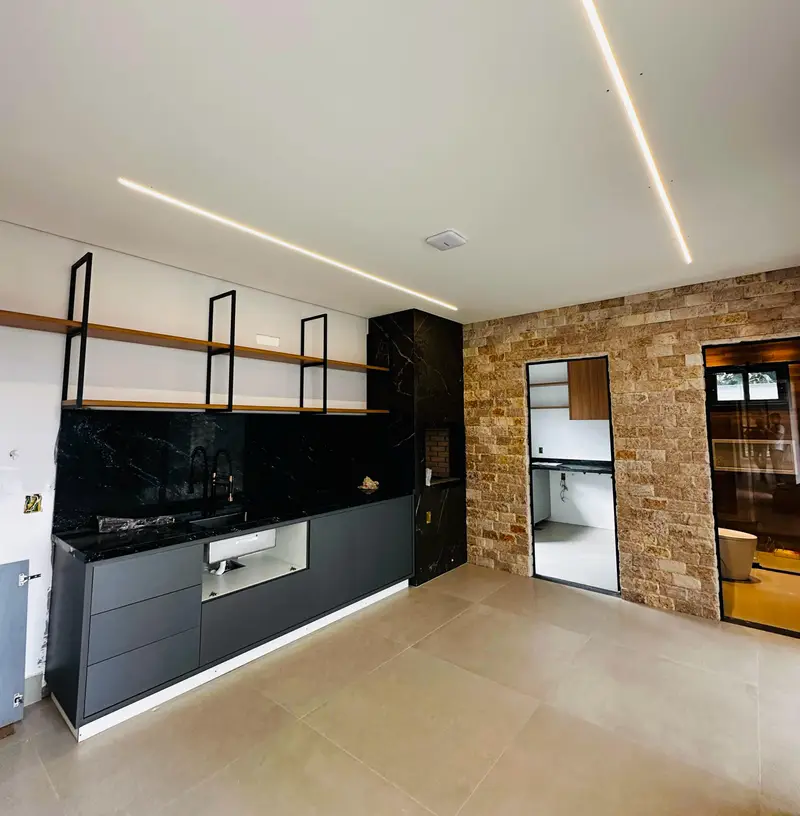 Área externa da casa em fase de acabamento, com grandes panos de vidro voltados para o quintal.